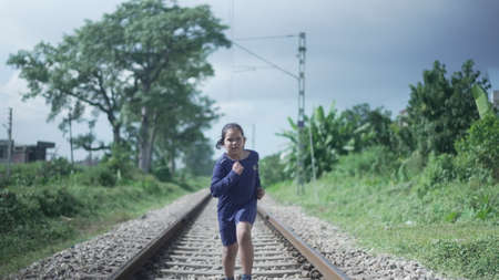 Indian Kid running on the railway track in the Himalayan range of India, greenery in the background. Physical fitness training. High-quality photoの写真素材