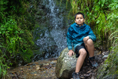 In the heart of nature, an Indian boy seated on a timeless stone.の写真素材