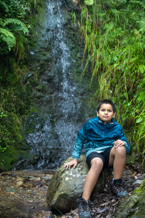 In the heart of nature, an Indian boy seated on a timeless stone.の写真素材