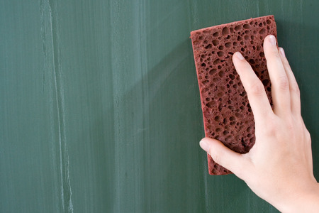 Female hand erasing a greenish blackboard.の写真素材