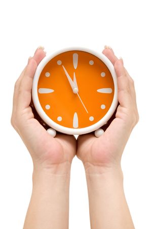 Hands holding an orange alarm clock. Showing five minutes to midnight. Isolated on a white background. Hands holding an orange alarm clock. Showing five minutes to midnight. Isolated on a white background.