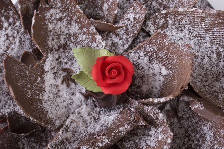 Top view close up of single red rose decoration on chocolate pieces with  sprinkled icing sugar on topの写真素材