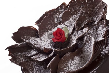 Decorative chocolate cake with red rose icing center and sprinkled icing sugar on topの写真素材