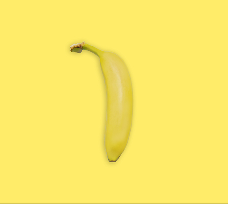 Yellow banana isolated on yellow background, top view. Minimalistic trendy image concept, bright summer color. Banana yellow summer background.の写真素材