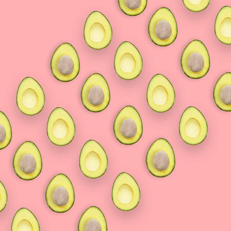 Avocado halves pattern isolated on pink background, top view conceptual image with space for text.