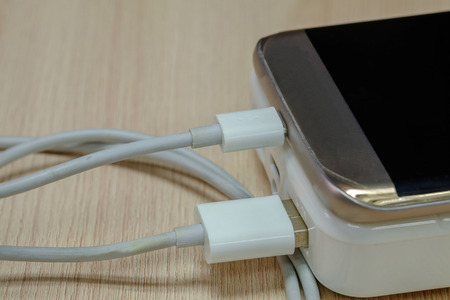 Charging smartphone with powerbank on wood.