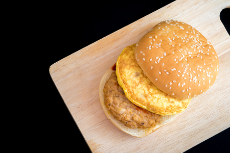 Pork and egg hamburger on wood and on black background.の写真素材