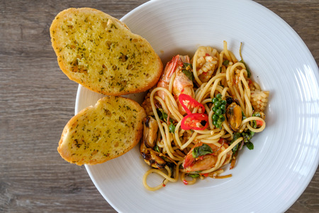 Top view the spicy seafood spaghetti in white plate in wooden table.の写真素材