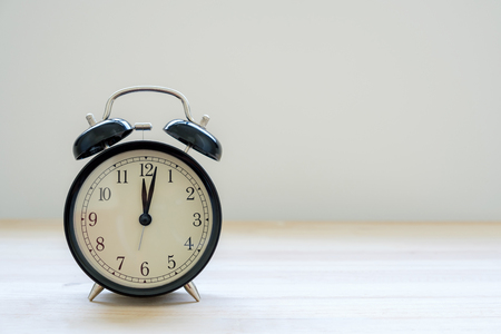 The midnight time from retro clock on wooden on gray background with copy space.