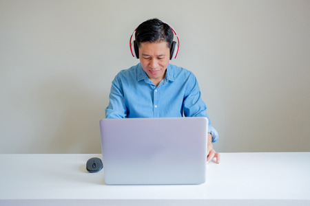 Smiling man wearing headphone when he using computer with copy space.の写真素材