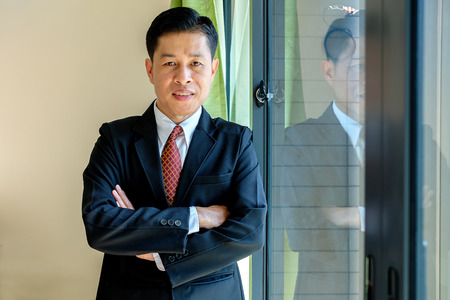 Handsome businessman in black suit smiles and standing in the office.の写真素材