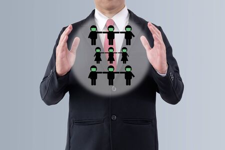 Between two hands of the businessman has little dolls wear mask and have distant together on gray background.の写真素材