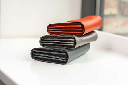 Three wallets of different colors on a white table