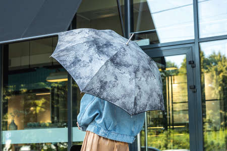 Girl in denim jacket with umbrella on background cafeの写真素材