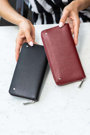 Two wallets in the hands of a girl on a white table