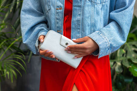 White wallet in the hands of the girl in redの写真素材