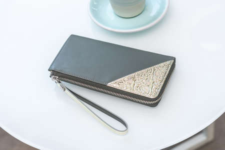 purse on a white table and a cup of coffeeの写真素材