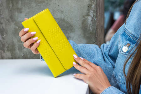 Yellow wallet on the table in the girls handsの写真素材