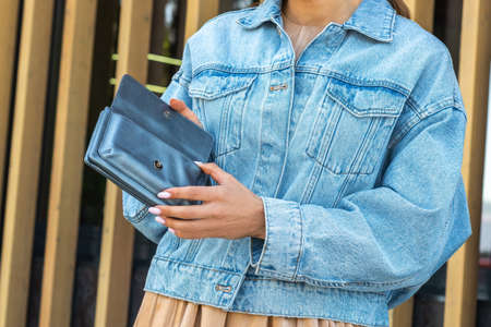 Girl in denim jacket holding blue walletの写真素材