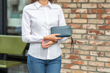 Girl in white holds a green wallet in her handの写真素材