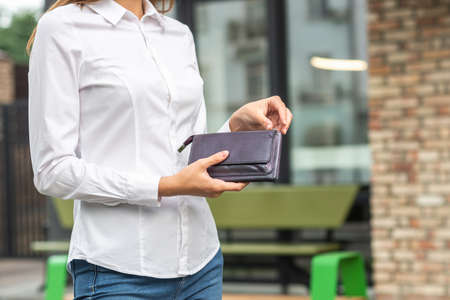Girl in white holds an open wallet in her handの写真素材