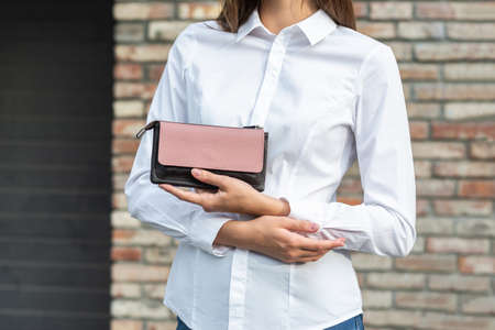 Girl in white holds a purse in her handの写真素材