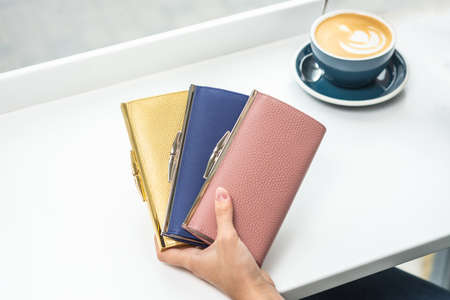 Three wallets in the girls hand on tableの写真素材