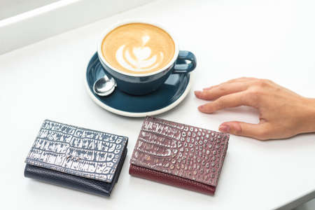 two purses with a cup of coffee on a white tableの写真素材