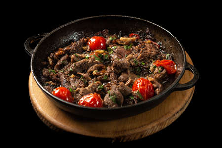 A frying pan with meat and vegetables on a trayの写真素材