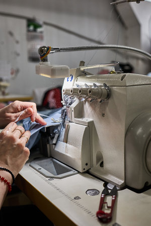 A skilled worker operates an industrial overlock machine, demonstrating the expertise required in...