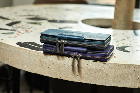Stylish leather wallets stacked on a textured table under natural light highlighting elegance and...