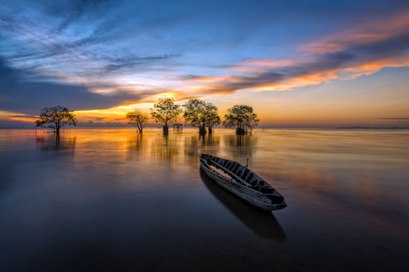 Fisherman boat and trees in the lake with beautiful morning light.の写真素材