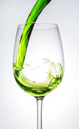 Green water being poured into glass on white backgroundの写真素材