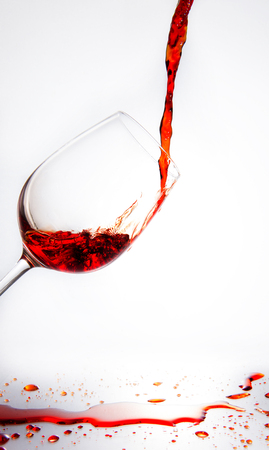 Red wine being poured into glass on white backgroundの写真素材
