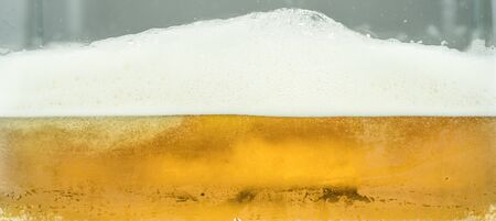 Close up of cool lager beer splash isolated on white background with realistic bubbles & froth in...