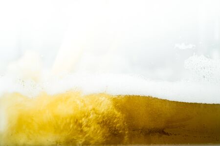 Close up of cool lager beer splash isolated on white background with realistic bubbles & froth in...