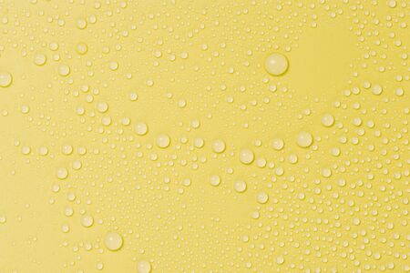 Close up of water drops on yellow tone background. Abstract orange wet texture with bubbles on plastic PVC surface or grunge. Realistic pure water droplets condensed. Detail of canvas leather textureの写真素材