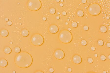 Close up of water drops on yellow tone background. Abstract orange wet texture with bubbles on...