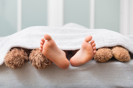 Young kid bare feet in bedの写真素材