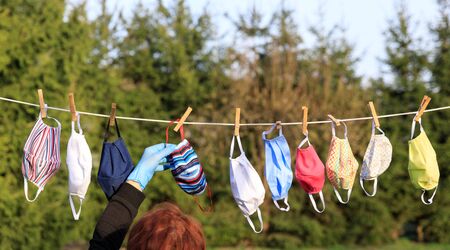 Hygienic mask hanging on the rack outdoor after being washed for cleanness and hygiene during Covid-19 virus outbreak . Hand made Anti Virus Mask to prevent COVID-19 coronary infestationの写真素材