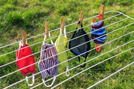 Drying mask hanging under the sun after use for disinfecting. Hygienic mask hanging on the rack outdoor after being washed for cleanness and hygiene during Covid-19 virus outbreakの写真素材