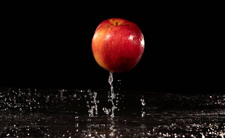 Water droplet on glossy surface of red apple on black backgroundの写真素材