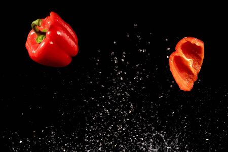 Tomato, Paprika and Eggplant slices fall into water, on black backgroundの写真素材