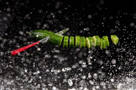Sliced cucumber with splashing water or explosion flying in the air isolated on black backgroundの写真素材