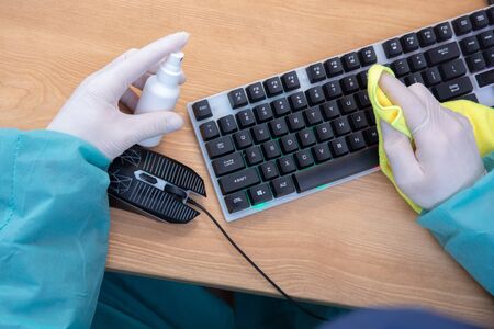 COVID-19 Coronavirusdisinfection of workspace surface of desk, keyboard, mouse at office. Stop the...