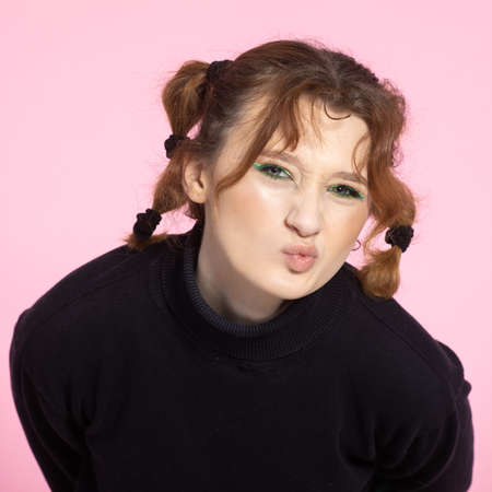 Friendly young woman with a vivacious smile and emotion . Young red-haired girl on pink background.の写真素材
