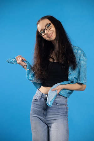 Young pretty girl woman laughing shyly and cheerfully, with a friendly and positive but insecure. Stylish girl in beautiful in the blue shirt.の写真素材