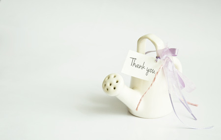 mini white ceramic watering can shaped pottery decorate with thank you white card and purple violet ribbonの写真素材