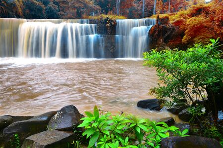 Photograph of beautiful waterfall with colorful trees in Thailand.