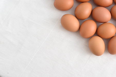 Fresh brown Eggs on white fabric background.